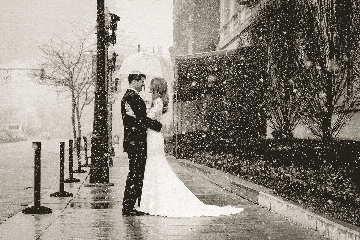 Bride and groom in winter blizzard snow storm.