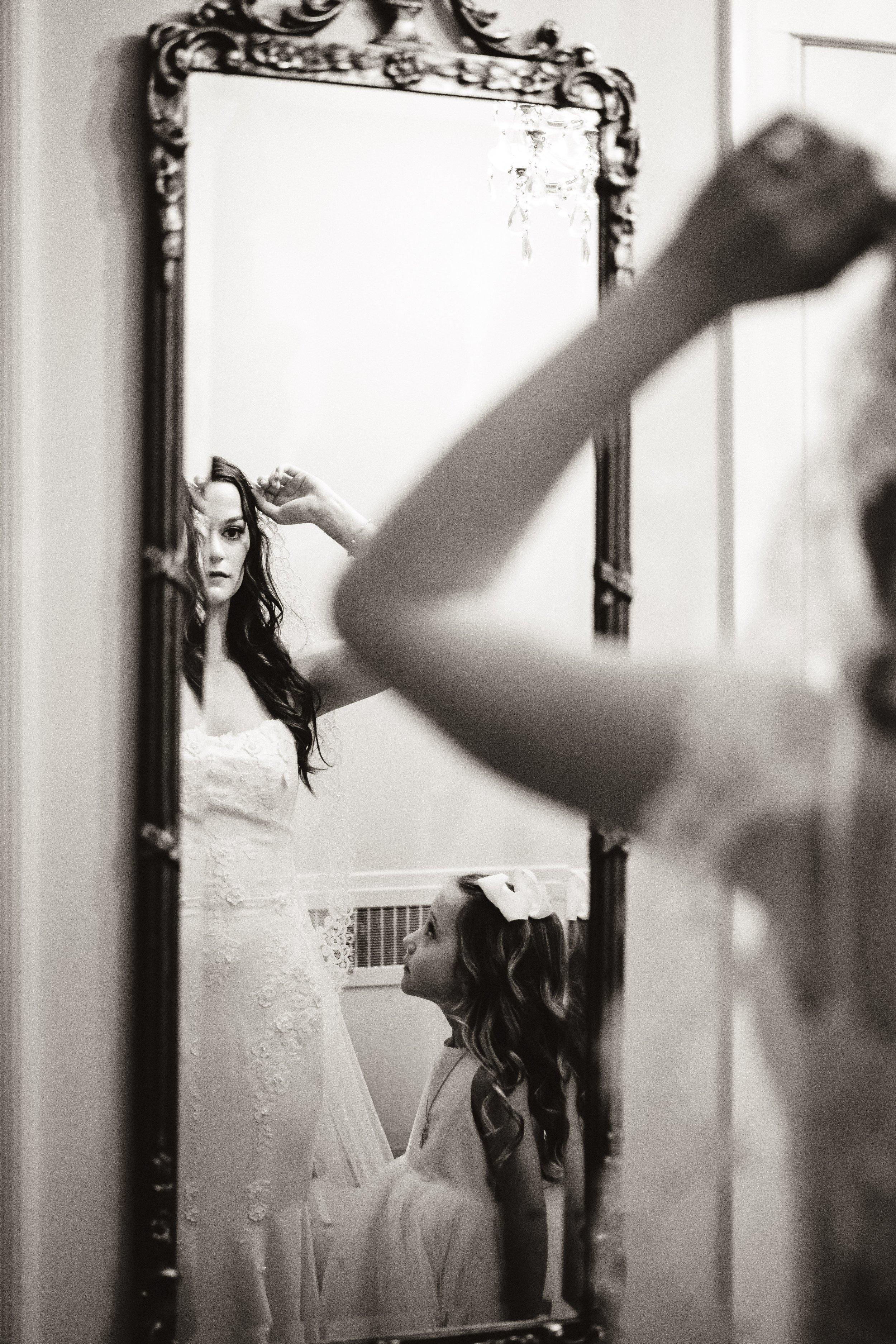 flower girl looking at bride mirror